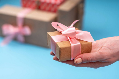 s hands holding gift box Packed in Kraft paper with pink ribbon 