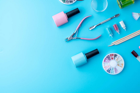 一套化妆品工具，用于专业的指甲护理，并在蓝色背景上创造美丽的设计。 上面的风景。 有文字地方的卡片作文