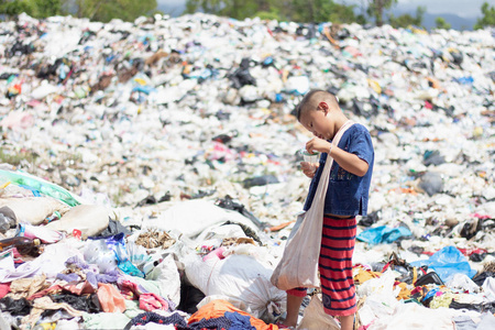 贫穷的男孩在口袋里收集垃圾以谋生，贫穷的孩子和贫穷的概念