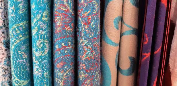 织物纹理特写镜头。一排围巾挂在铁轨上。看起来五颜六色和抽象。编织纹理