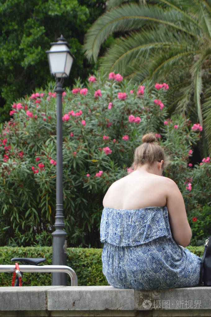 胖女孩穿着衣服,赤裸的背,疲惫的放松和日光浴,坐