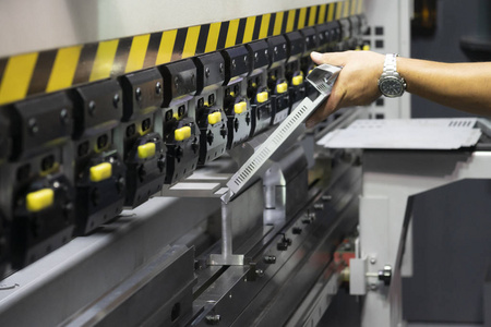 技术人员使用液压折弯机. 钣金制造工艺.照片