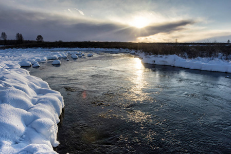 夕阳下一条河边的冬景与雪腐