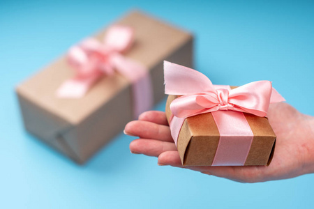 s hands holding gift box Packed in Kraft paper with pink ribbon 