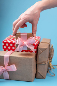 s hands holding gift boxes Packed in Kraft paper with pink ribbo