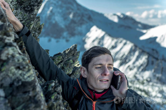 一个年轻人爬上山顶,手里拿着电话说话.