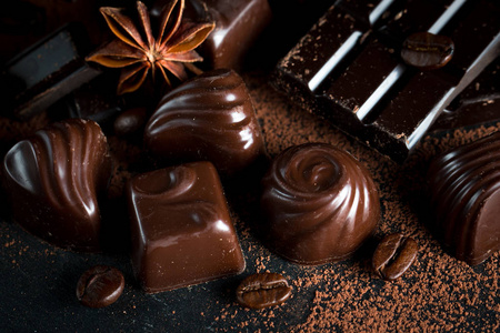 黑白色和牛奶巧克力叠片的种类。 巧克力和咖啡豆在乡村木制的背景上。 香料肉桂。 选择性宏观聚焦。 巧克力背景。 糖果