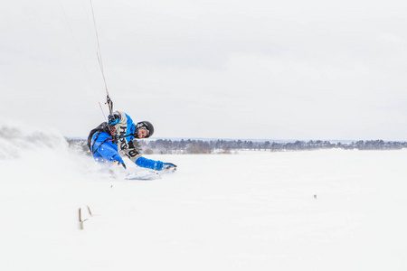 穿着蓝色冬季服装和头盔的年轻女子白天骑在滑雪板上