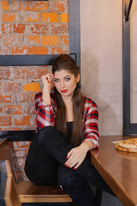 美丽和的女孩坐在一张桌子上与比萨饼在咖啡馆