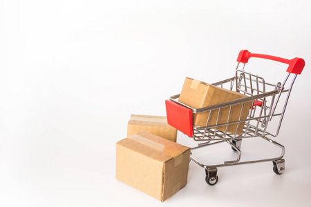 购物概念白色背景下红色购物车中的纸箱或纸盒。网上购物消费者可以从家里购物和送货服务。副本空间