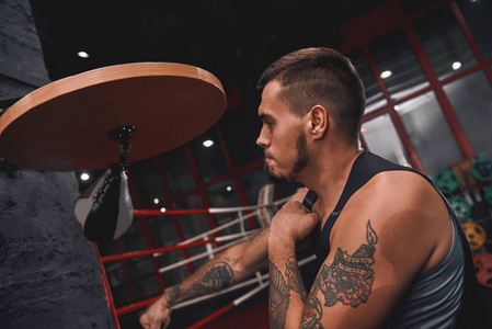 训练拳击技能时, 穿着运动服的肌肉纹身拳击手在打速度袋时打打拳照片