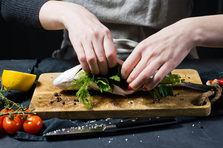 s hands stuffed Dorado fish on a wooden chopping Board with pars