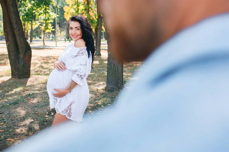 怀孕的女孩和她的丈夫一起在公园里散步，享受美丽的天气。