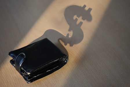 办公桌上一个黑色钱包美元形式的阴影