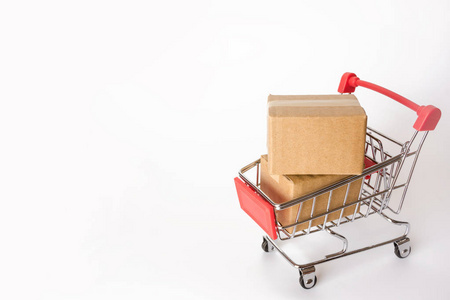购物概念白色背景下红色购物车中的纸箱或纸箱。 网上购物消费者可以从家里购物和送货服务。 副本空间