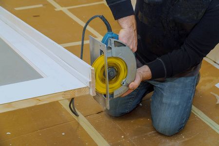 s hands holding circular saw and preparing to make a cut in door