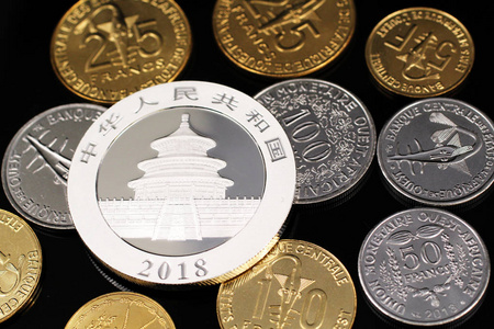 一个宏观图像的各种西非法郎硬币和一个银色的中国一盎司硬币在反光