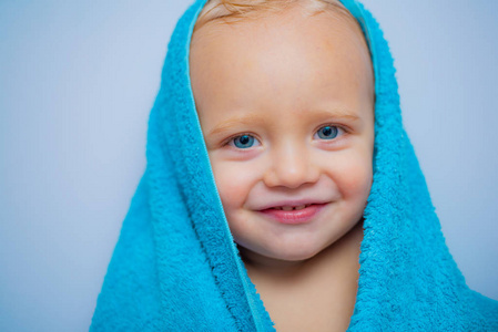 小婴儿在一条白色毛巾下微笑。微笑的男婴在家里洗澡。愉快的沐浴时间