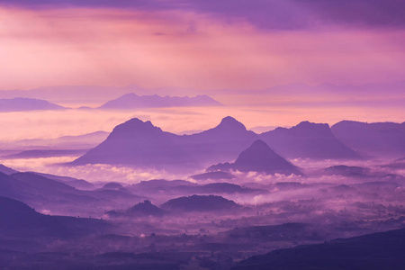 雾蒙蒙的风景山，紫色的天空和朝阳初升的山峦轮廓山脉背景