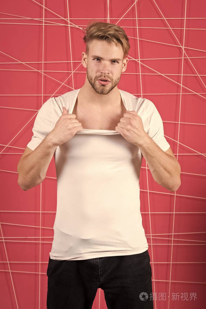 男子用刚毛严格集中面部脱衣服, 粉红色背景.