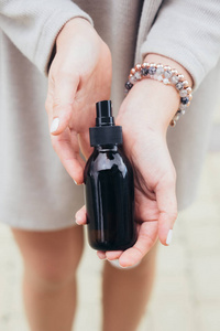 s hands holding glass brown bottle with spa cosmetics. Beauty bl