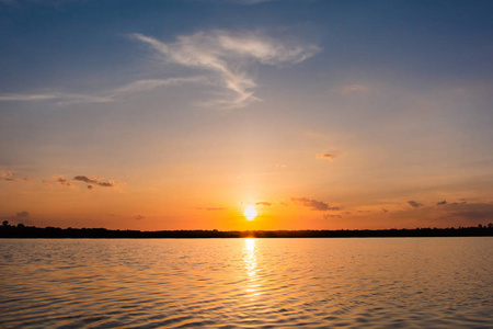 湖面上的日落。 美丽的日落背后的云层上方的湖面景观背景。 日落时乌云密布的戏剧性天空
