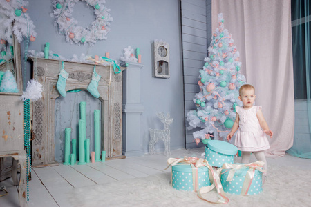 一个可爱的欧洲金发小公主的肖像，戴着一件漂亮的连衣裙，在一个装饰着圣诞主题的工作室里打开礼物，里面有玩具和圣诞树
