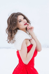 穿着鲜红裙子的女孩在雪地上。 冬季肖像画