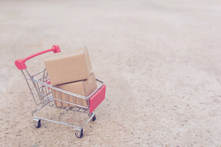 购物概念纸箱或纸箱在购物车在混凝土地板上。 网上购物消费者可以从家里购物和送货服务。 复制空间