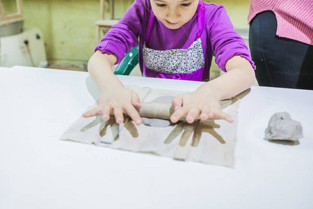 有创造力的孩子在陶器车间用粘土工作.照片