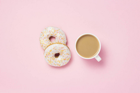 白色杯子咖啡或茶与牛奶和新鲜美味的甜面圈在粉红色背景。 烘焙理念，新鲜糕点，美味的早餐，快餐。 平躺式顶部视图
