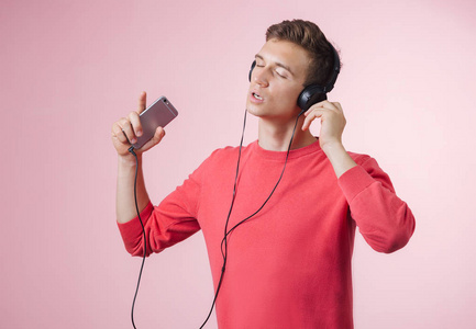 一个拿着耳机听音乐的年轻帅哥的肖像用智能手机