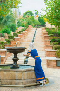 女孩触摸在一个古老的喷泉的水