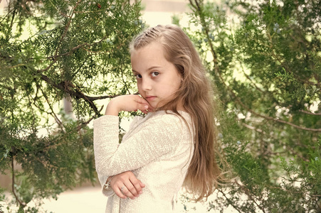 儿童模型与新鲜的面孔皮肤在夏天自然。穿着时髦衣服的女孩在绿树上摆姿势。小孩长着金色长发。时尚美和发型。护肤和新鲜度