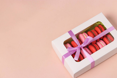 美味的甜饼干通心粉，粉红色背景的白色礼品盒中的通心粉，红色和粉红色的通心粉。复制空间