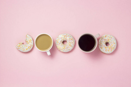杯子和纸杯，咖啡或茶，新鲜美味的甜甜圈暴露在粉红色的背景上。 快餐概念面包店早餐糖果咖啡店。 平躺顶视复印空间