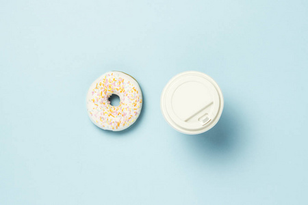 新鲜美味的甜面圈和纸杯，咖啡或茶在蓝色背景。 快餐概念面包店早餐。 极简主义。 平躺式顶部视图