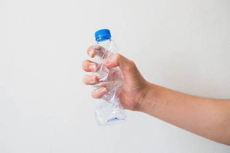 手拿一个可回收的塑料瓶在白色的背景.照片
