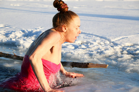 一个美丽的年轻女孩，红头发，一件泳衣潜入冰冷的水在冬天的湖面上，在一个美丽的阳光明媚的日子。 乌克兰苏米州什斯特卡