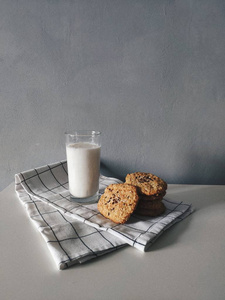 燕麦片饼干, 在灰色背景上的白色毛巾上加一杯牛奶。早餐时间