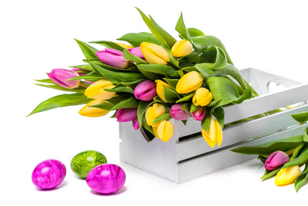 复活节。 多种颜色的复活节彩蛋。 白色盒子里的五颜六色的郁金香。 春天的花束。 黄色和紫色郁金香。 恭喜。 春天。 在白色背景下