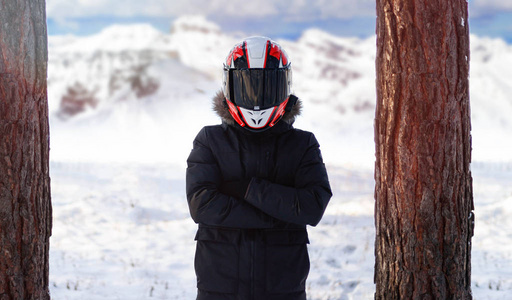 骑摩托车的人穿着冬天温暖的夹克在冬天的森林里。