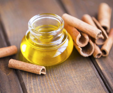 肉桂油与肉桂棒的木质背景特写选择性焦点芳香精油照片