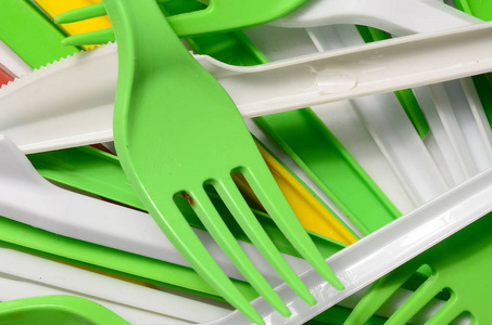 一堆明亮的黄色绿色和白色的塑料厨具。 生态问题。 塑料污染