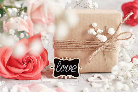 礼品袋小黑板和花红色玫瑰和白色小花在灰色背景
