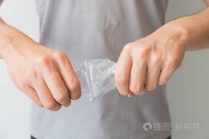 两只手在隔离的白色背景下扭曲透明塑料瓶,包括裁剪路径,在回收全球