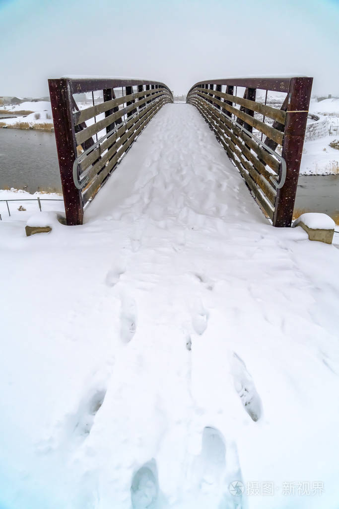 在雪中的脚步通向犹他州的一座桥