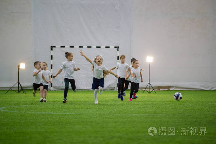 小孩子在室内踢足球.兴奋的儿童足球队在赛场上奔跑