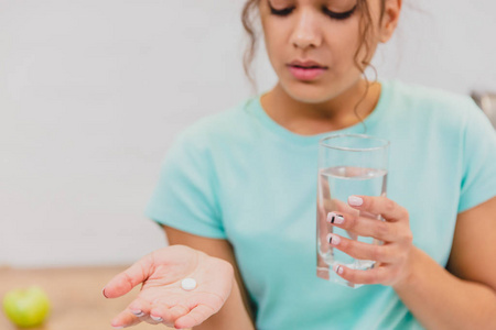 手拿着药丸和一杯水的妇女服用紧急药物补品或抗生素抗抑郁止痛药, 以