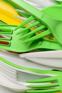 一堆明亮的黄色绿色和白色的塑料厨具。 生态问题。 塑料污染
